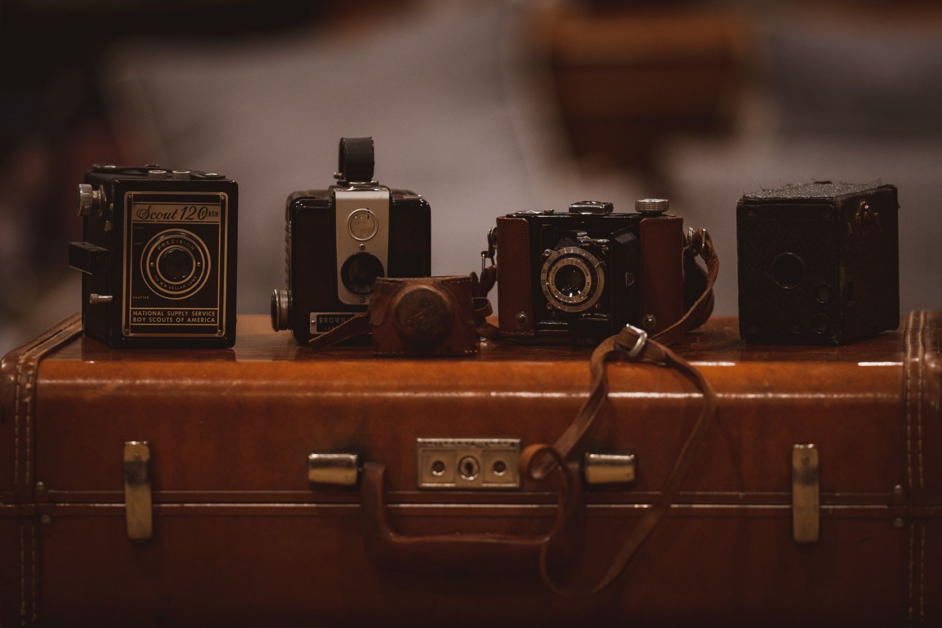 Four Assorted-color Cameras on Brown Suitfcase